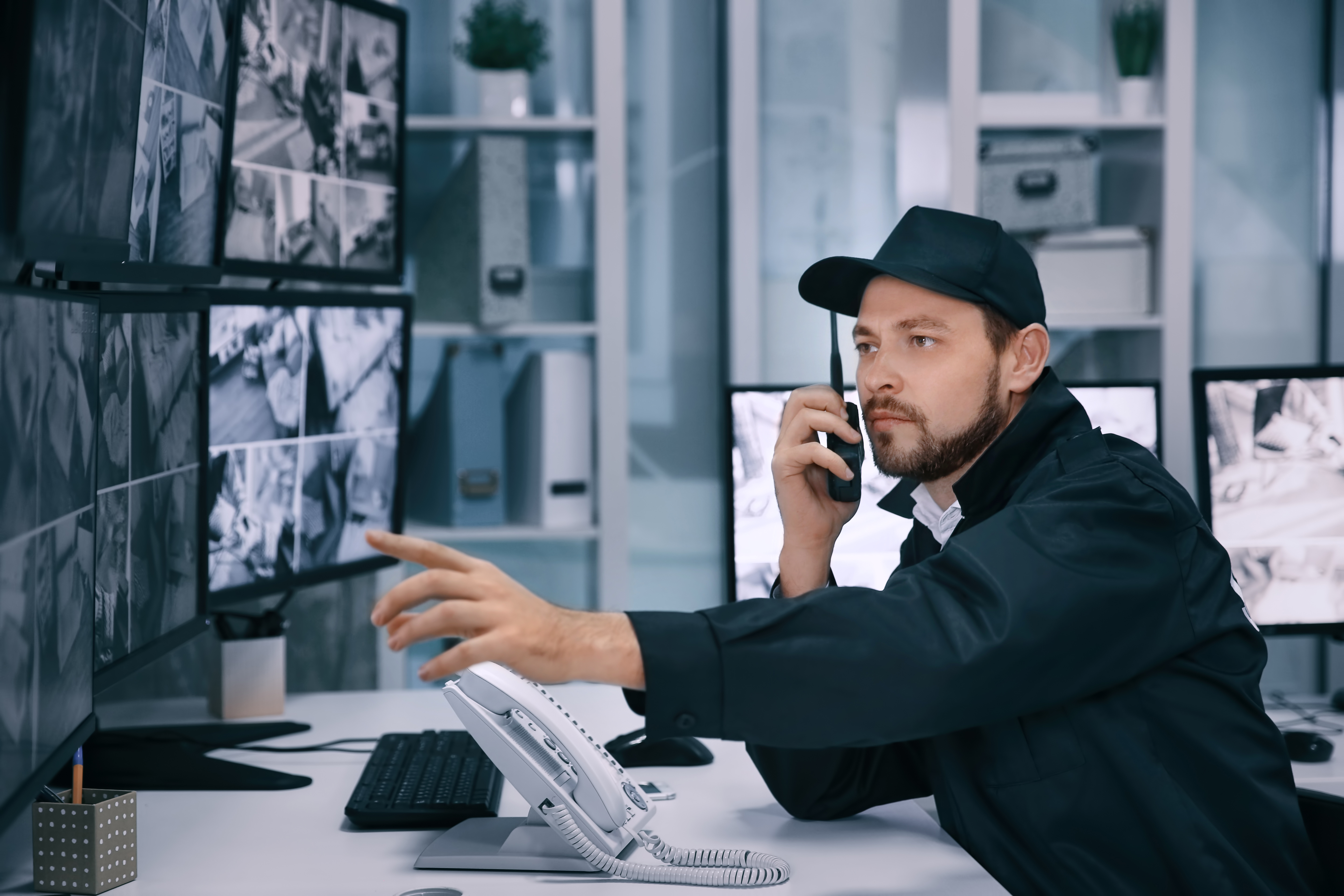 Male security guard using radio transmitter in surveillance room